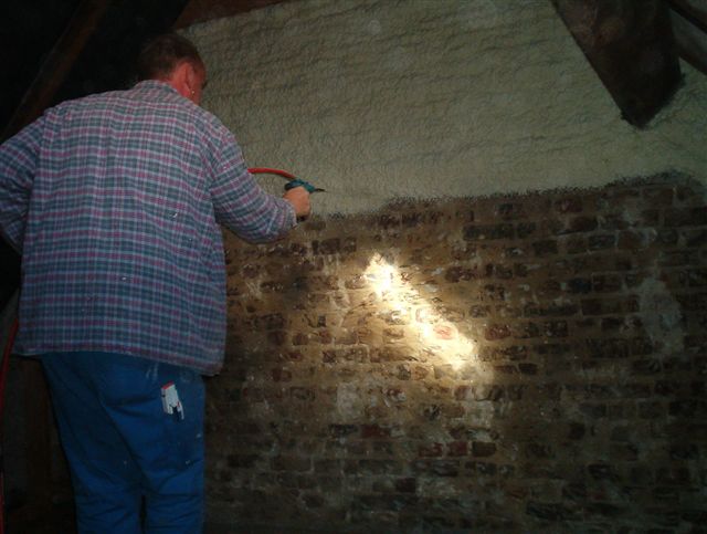 Brick wall being spray foam insulated